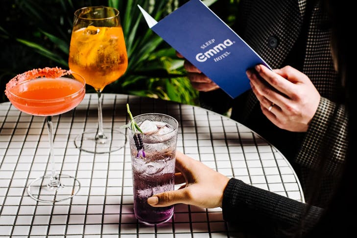 Two people dining at a white tiled table, both sipping on margaritas.
